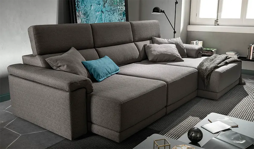 divano elegante di colore grigio con sedute estraibili e poggiatesta reclinabili.