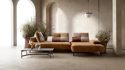 Divano modulare dal design contemporaneo, rivestito in tessuto caldo nei toni del marrone, con sedute ampie e linee essenziali, ideale per ambienti eleganti e luminosi.