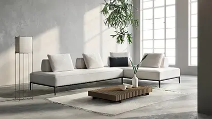 Divano modulare dal design contemporaneo, rivestito in tessuto nei toni del grigio chiaro, con sedute ampie e linee essenziali.