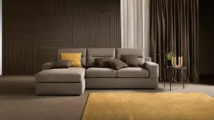 Divano angolare moderno con linee semplici, in tessuto grigio, abbinato a un tappeto giallo in un ambiente living elegante.