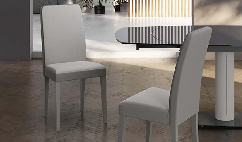 Sedia con seduta in similpelle colore grigio chiaro e gambe in legno di faggio laccato.